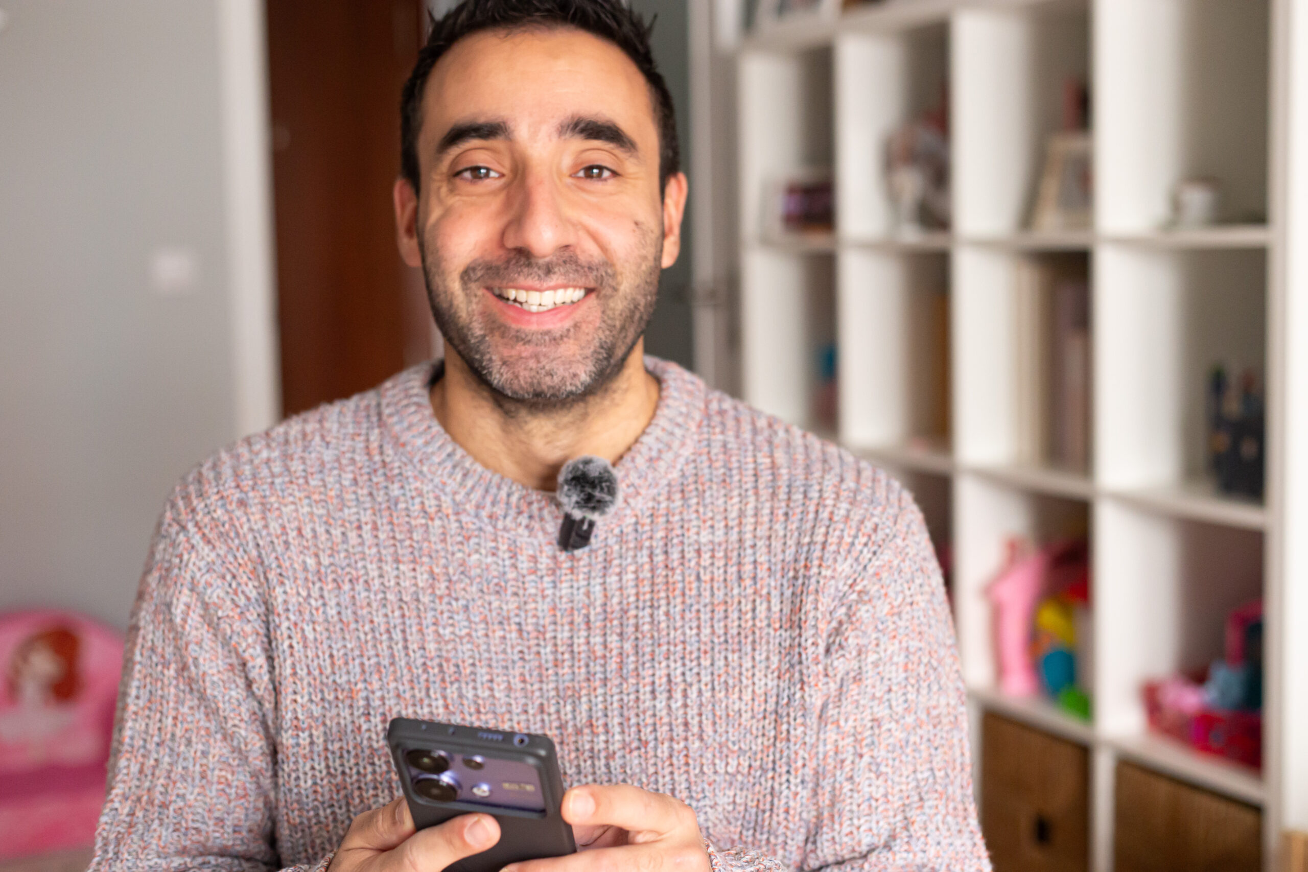 Ismael Molina con su móvil sonriendo a cámara como community manager